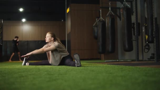 Mulher fitness ambicioso fazendo divisões no ginásio. ajuste menina aquecimento até no esporte clube — Vídeo de Stock