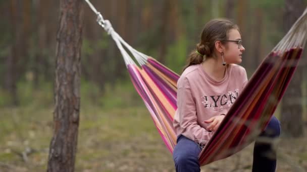 Tonårstjej som kopplar av i hängmatta under träd. Kvinnlig tonåring vilar i helgen — Stockvideo