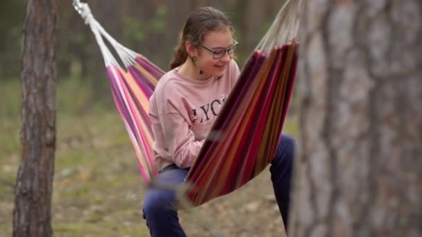 Nastolatka huśtawka w hamaku z radosnym nastroju w lesie. — Wideo stockowe
