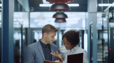 Çok ırklı çift koridorda tablet kaydırıyor. Çift projeden bahsediyor.