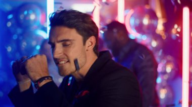 Neon ışıklı arka planda takılan çekici bir adam. Disko partisinde dans eden adam.