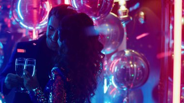 Arka planda neon lambalarla sarılan tatlı bir çift. Kulüpte dans eden kadın ve erkek.