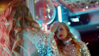Partide aynanın yanında dans eden tatlı bir kadın. Kulüpte kendini muayene eden kız.