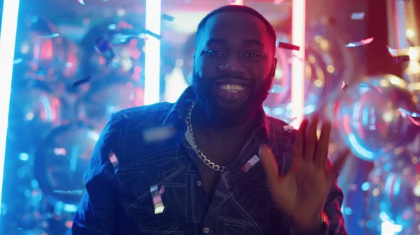 Un africano sonriente bailando bajo el confeti. Hombre moviendo cuerpo y mano en el club —  Fotos de Stock