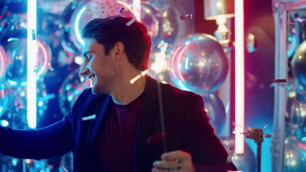 Positive guy holding sparkles in nightclub. Man dancing under confetti