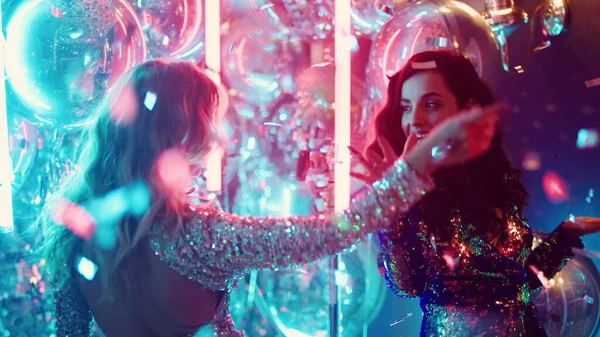 Neon lambaların arkasında dans eden çekici kadınlar. Kızlar geceyi partide geçirir. — Stok fotoğraf