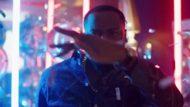 Partide diskoda eğlenen yakışıklı afro adam. Adam hareket ediyor ve sopayı tutuyor.