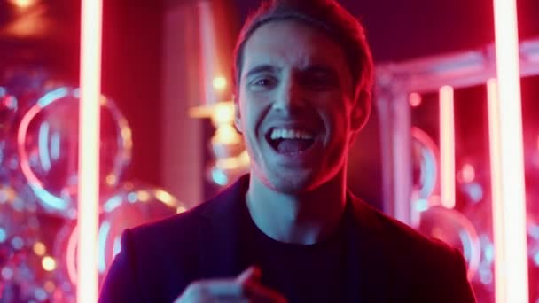 Fröhlicher Typ, der im Nachtclub lächelt. Männliche Person lacht auf Neonlicht Hintergrund — Stockvideo