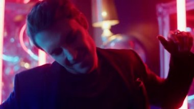 Neşeli adam partide hareketler yapıyor. Neon arka planda müziği seven adam