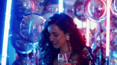 Neon arka planda alkolle dans eden mutlu kadın. Kulüpte kutlama yapan kız.