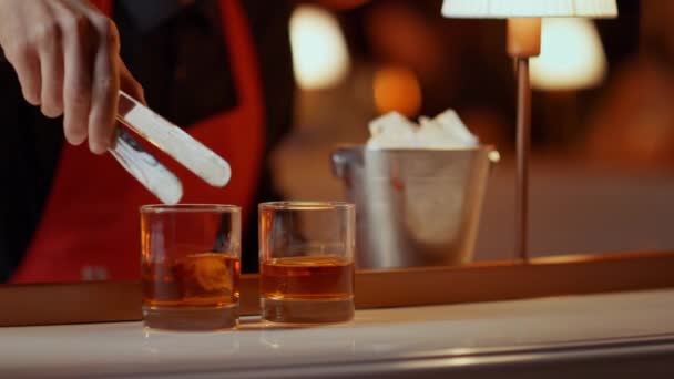 Barman prépare du whisky pour les gens en boîte de nuit. Homme mettant des glaçons — Video