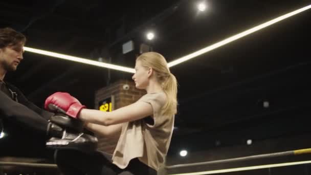 Агітована спортивна жінка практикує ноги ударів по боксерському кільцю. Підійде для дівчаток бокс в спортзалі — стокове відео