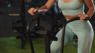 Spor salonunda egzersiz bisikleti kullanan formda bir kız. Spor salonunda bayan sporcu eğitimi.