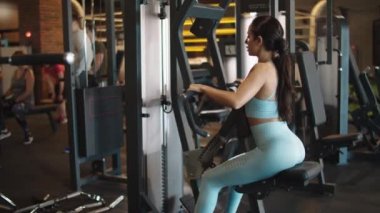 Spor kulübünde ısınan hırslı fit kız. Spor kızı spor salonunda biseptik kıvrımlar yapıyor.