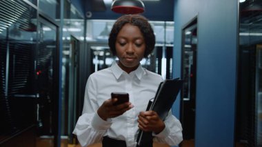 Koridorda telefon görüşmesi yapan Afro bir kadın. Afrikalı kadın ofiste mesajlaşıyor.
