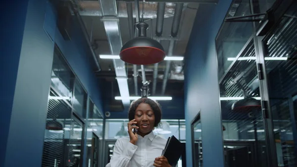 Весела афро-жінка використовує телефон в коридорі. Жінка розмовляє по телефону в офісі — стокове фото