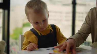 Kardeşler evde birlikte vakit geçiriyorlar. Masada masa başında oturan kardeşler.