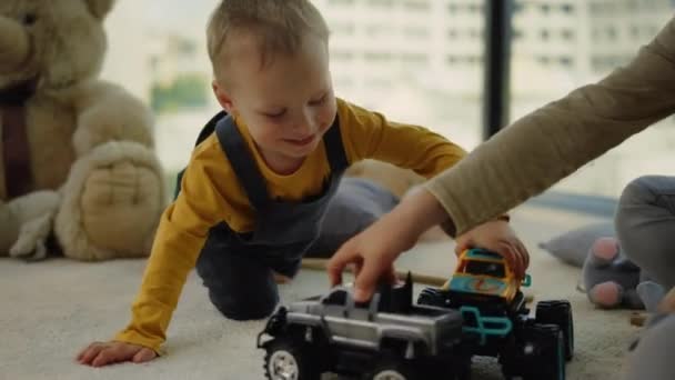 Счастливые мальчики устраивают гонки с игрушечными машинами дома. Веселый мальчик играет в помещении. — стоковое видео
