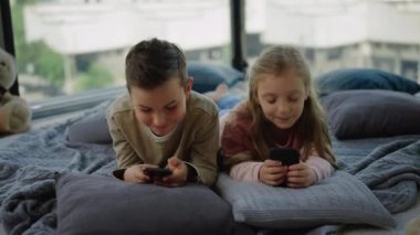 Mobil oyun bağımlısı hilekar çocuklar. Kardeşler evde akıllı telefonlarla oynuyorlar..