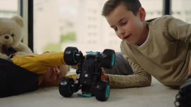 Niños felices jugando con coches de juguete en la alfombra. Hermanos divirtiéndose en casa. — Vídeos de Stock