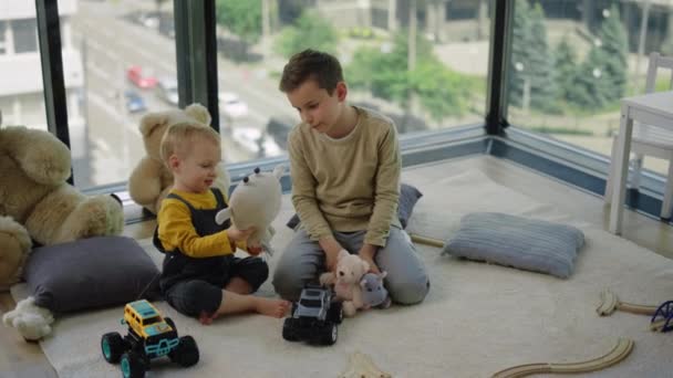 Zwei Brüder spielen mit Plüschtieren. Liebenswerte Kinder, die zu Hause auf Teppich sitzen. — Stockvideo