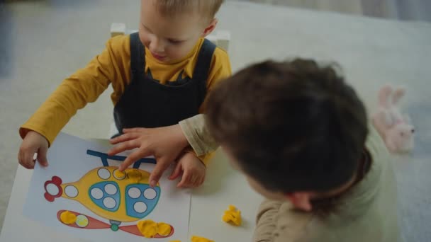 Lindos hermanos haciendo cuadro de arcilla a casa. Hermano mayor ayudando a modelar más joven. — Vídeos de Stock