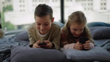 Kardeşler içeride oyun oynuyorlar. Akıllı telefon ekranı arayan arkadaşlar.