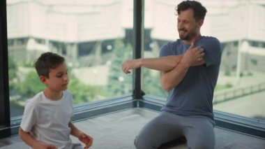 Baba oğul halının üzerinde geriniyor. Erkek ve çocuk evde antrenman yapıyor..
