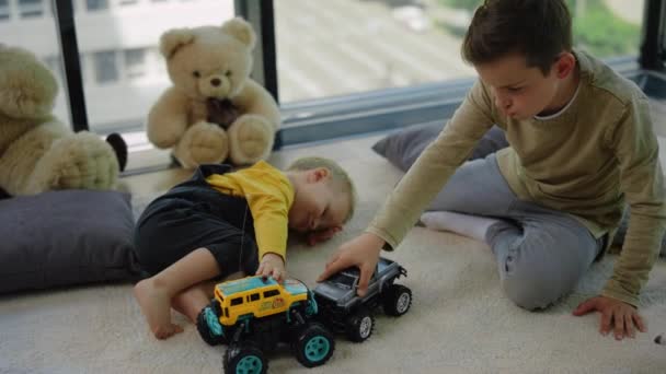 Zwei Geschwister genießen Indoor-Spiele. Schöne Kinder spielen Spielzeug-Monstertrucks. — Stockvideo