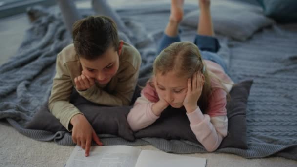Bratr a sestra studují s učebnicí doma. Sourozenci dotýkající se stránek — Stock video