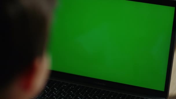 Парень использует компьютер с зеленым экраном. Школьник ищет нетбук с зеленым экраном. — стоковое видео