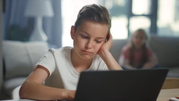 Школярка використовує ноутбук для електронного навчання вдома. Милий хлопчик дивиться відео урок . — стокове відео