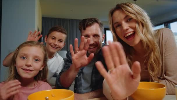 Ouders, kinderen op zoek naar camera thuis. Familie zwaaiende handen tijdens de ochtend videogesprek — Stockvideo