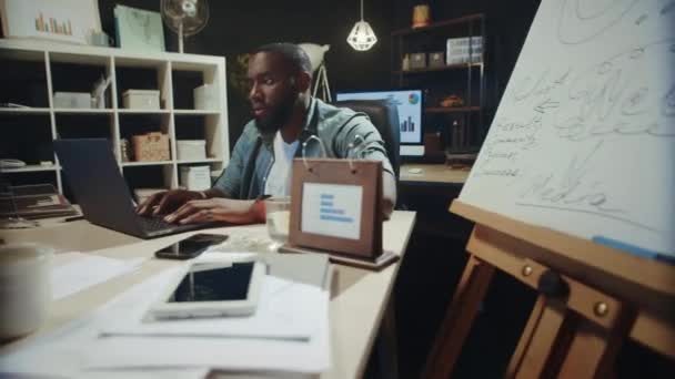 Spännande afrikansk kille som letar laptop på kontoret. Afro man får goda nyheter — Stockvideo