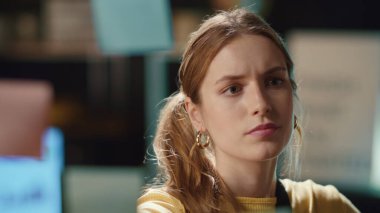 Odaklanmış hipster kız portresi. Gece ofisindeki cam panoda çıkartma okuyor.