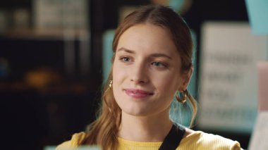 Gülümseyen iş kadını hippi ofisindeki cam levhadan çıkartma çıkartıyor.