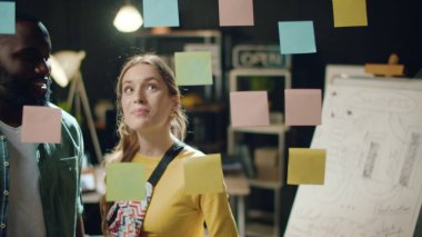 Yakın plan melez çift gece ofisinde projeyi tartışıyor.