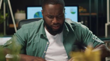 Afrikalı iş adamı içeride belge okuyor. Kızgın afro adam diyagrama bakıyor.