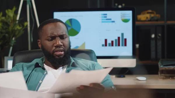 Nahaufnahme betont afrikanischen Mann suchen Papiere im Amt. Afro-Typ überprüft Daten — Stockfoto