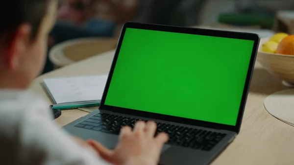 Rapaz desconhecido a usar um computador de limpeza em casa. Schoolboy olhando tela verde laptop — Fotografia de Stock