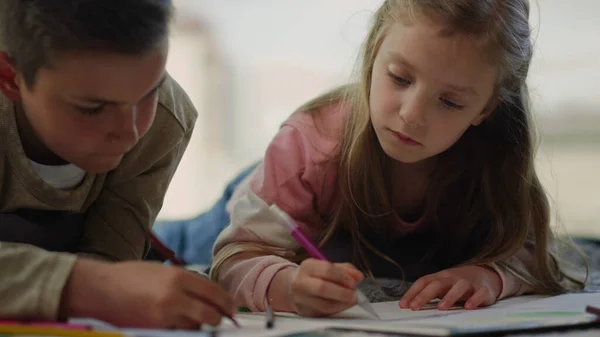 Kinderen schilderen thuis met kleurpotloden. Broers en zussen die schetsboeken gebruiken. — Stockfoto