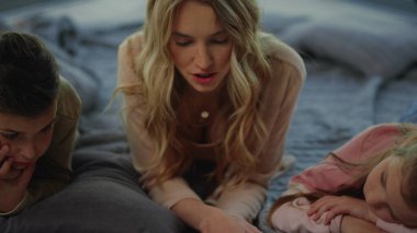 Anne çocuklarla evde vakit geçiriyor. Kızın oğlu dinliyor, anne okuyor..