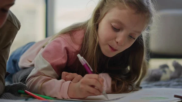 Schattig meisje kleurplaat met potloden. Zuster tekening naast broer binnen. — Stockfoto