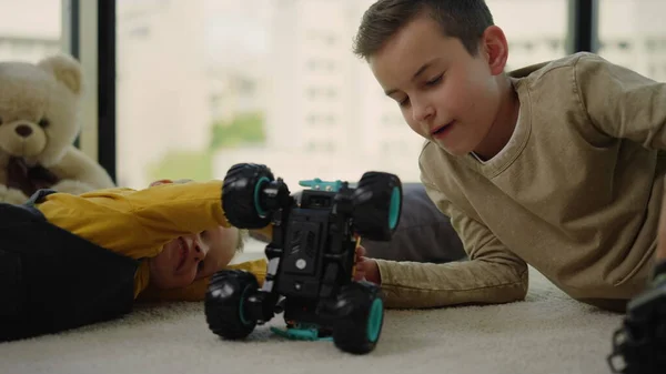 Gelukkige schildren spelen met speelgoed auto 's op tapijt. Broeders die zich thuis vermaken. — Stockfoto