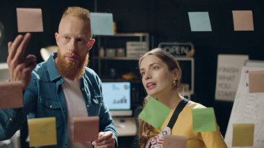 Genç iş kadını, hipster ofisinde erkek meslektaşıyla fikirleri tartışıyor.