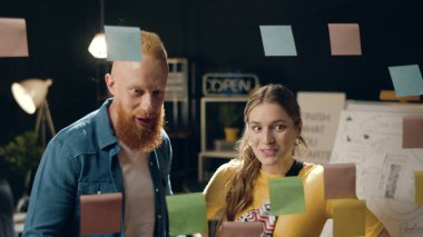 Yakın plan tatmin olmuş erkek ve kadın profesyoneller gece ofisinde beşlik çakıyor.