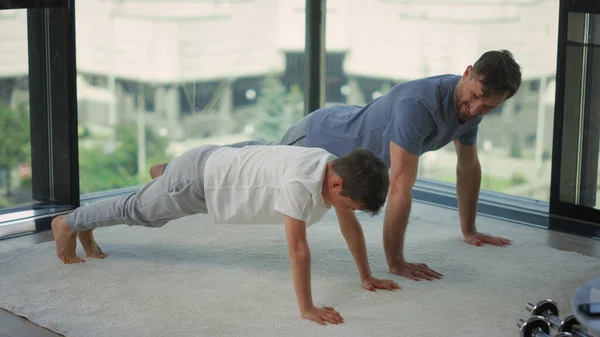 Pai e filho se exercitando juntos. Homem e menino fazendo flexões em casa. — Fotografia de Stock