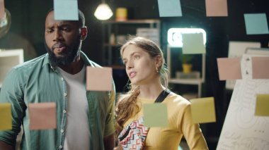 Yakın plan, hipster ofisindeki çıkartmalara bakan çok ırklı çifte odaklanmış durumda.