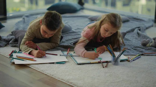Testvérek rajzolnak színes ceruzákkal. Gyerekek otthon művészkednek.. — Stock Fotó