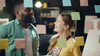 Çok ırklı iş adamı ve iş kadını hippi ofisinde konuşuyor.